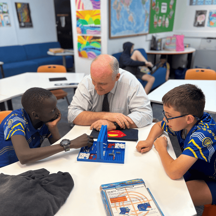 Principal Peter South watching two students play board game
