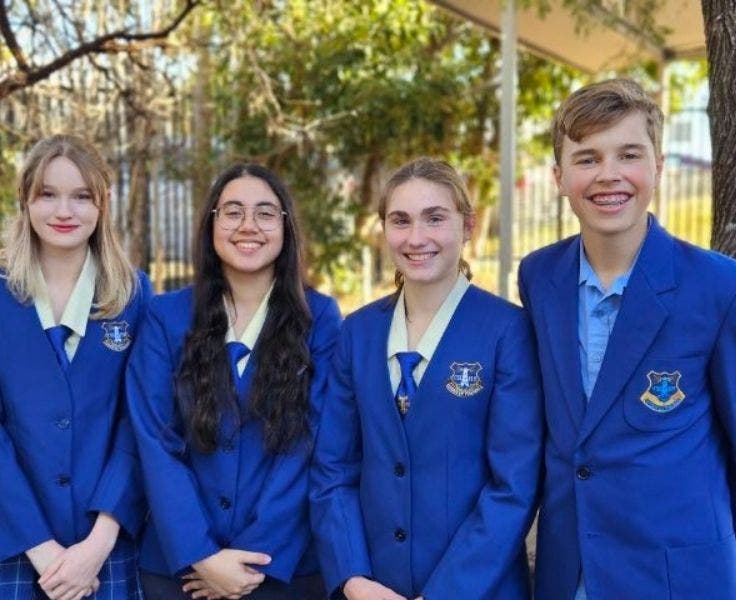 Proud debating team of three girls and one boy in formal school uniform